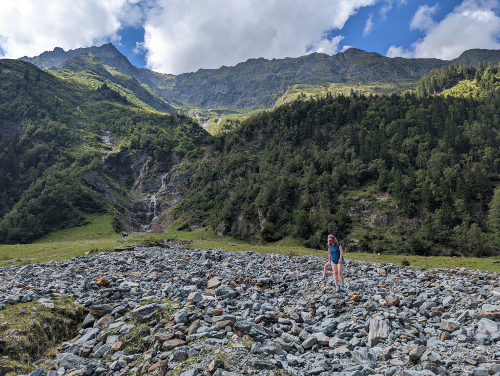 Kind wandert über ein großes Geröllfeld oberhalb der Schösswendklamm, umgeben von beeindruckender Bergkulisse im Nationalpark Hohe Tauern.