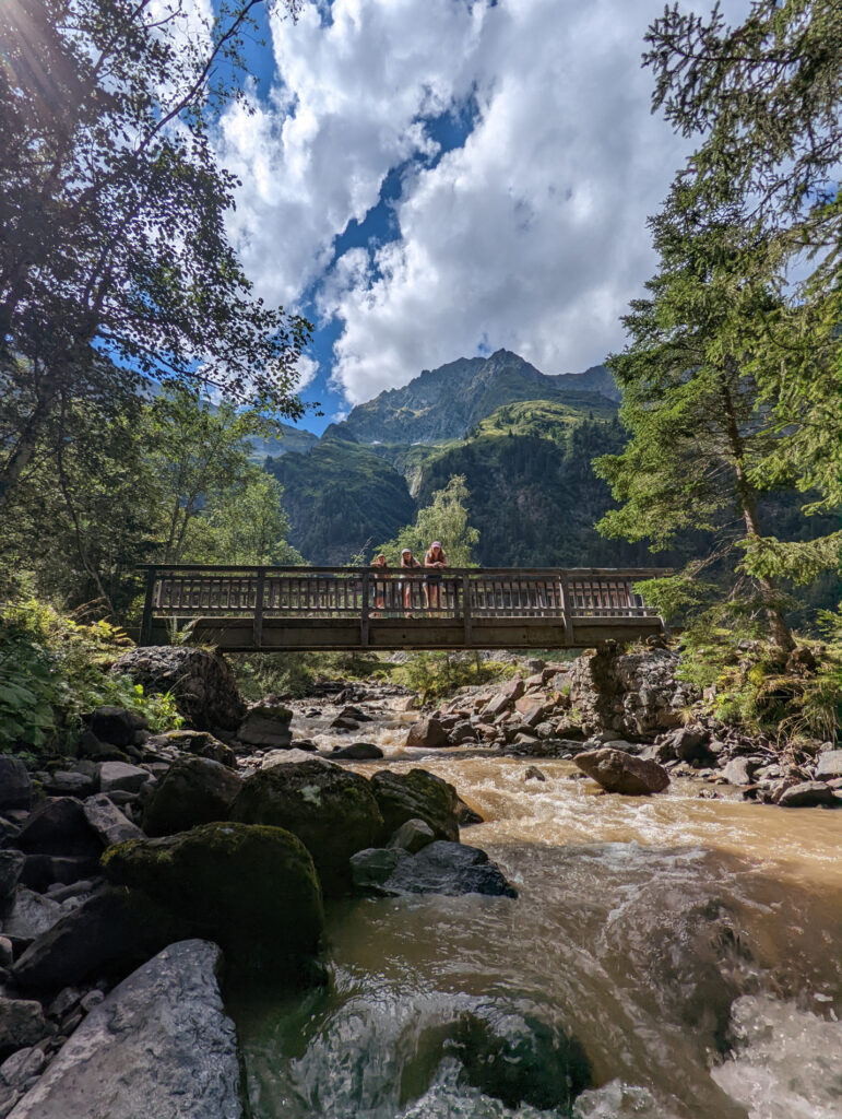 Familie steht auf einer Holzbrücke über dem tosenden Wasser in der Schösswendklamm, ein spannendes Abenteuer im Familienurlaub.