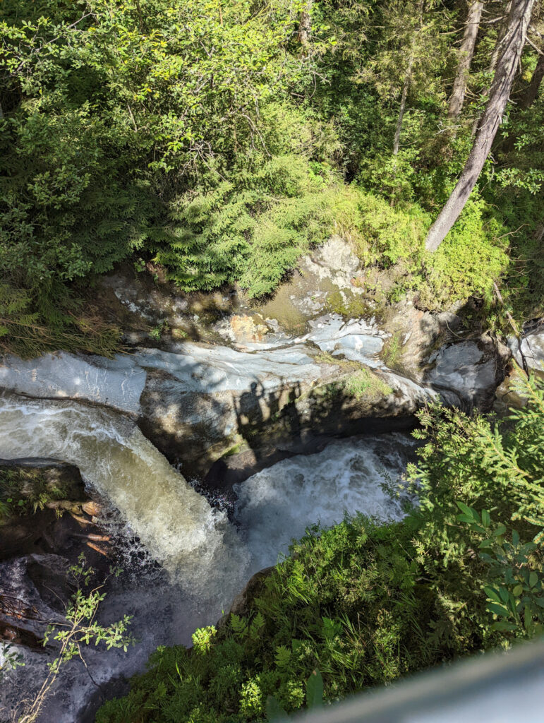 Tiefblick auf das rauschende, türkisblaue Wasser der Schösswendklamm, umgeben von grünem Bewuchs.