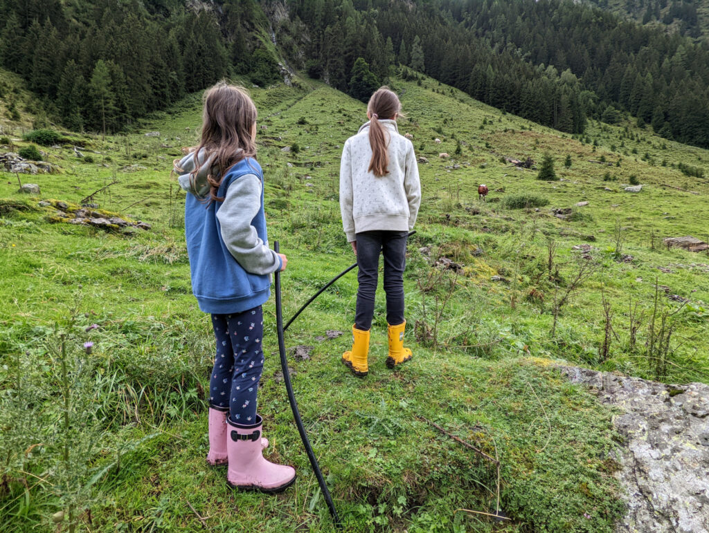 Kinder helfen beim Kühe-Eintreiben auf der Alm – ein Erlebnis im Familienurlaub im Nationalpark Hohe Tauern.