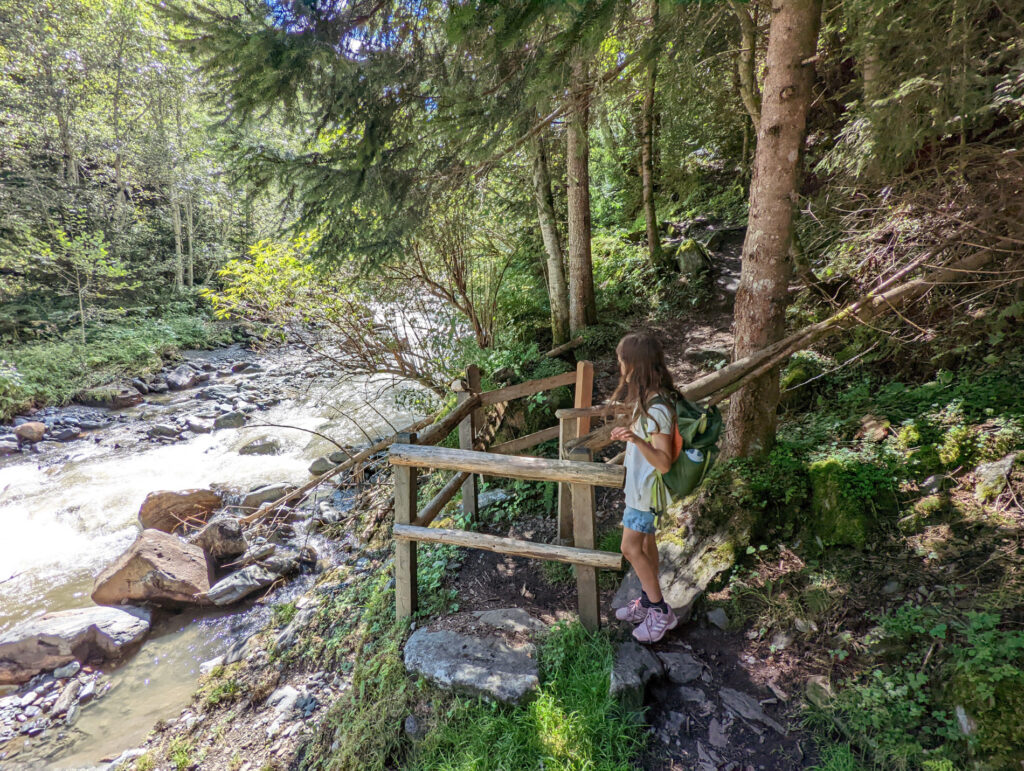 Mädchen steht am Geländer und blickt auf die Wassermassen in der Schösswendklamm, ein beeindruckendes Erlebnis für Familien.