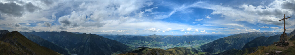 Panoramablick vom Zwölferkogel über ein weites Tal und die umliegende Bergwelt des Nationalparks Hohe Tauern. Ideal für Wanderurlaub.